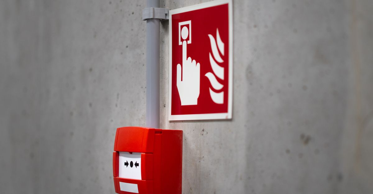 Red fire alarm button and sign on a concrete wall for emergency safety indoors.