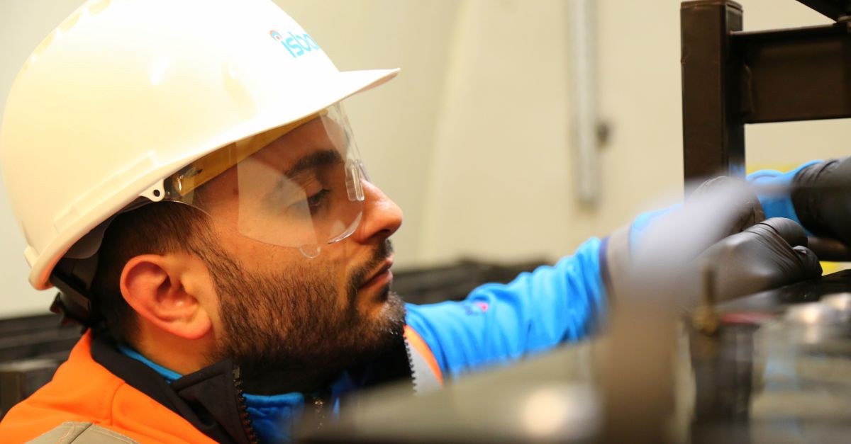 Close-up of a construction worker wearing safety gear while focusing on a task indoors.