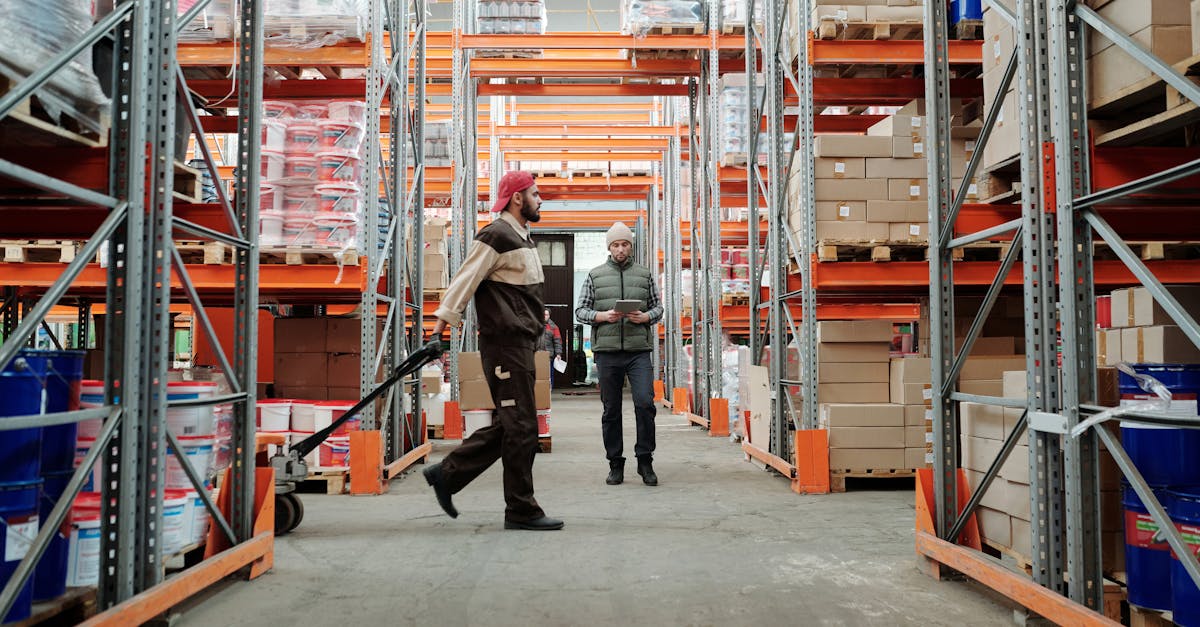 Two workers manage inventory in a spacious warehouse aisle.