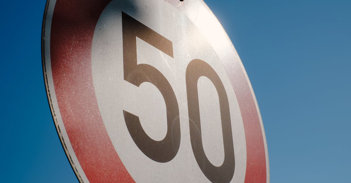 A close-up of a speed limit sign displaying 50 against a clear blue sky backdrop.