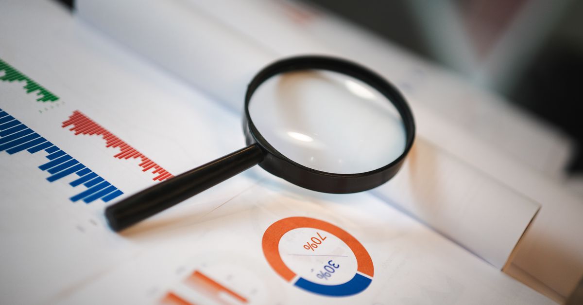 An image showcasing a magnifying glass placed on financial graphs and charts depicting statistical data.