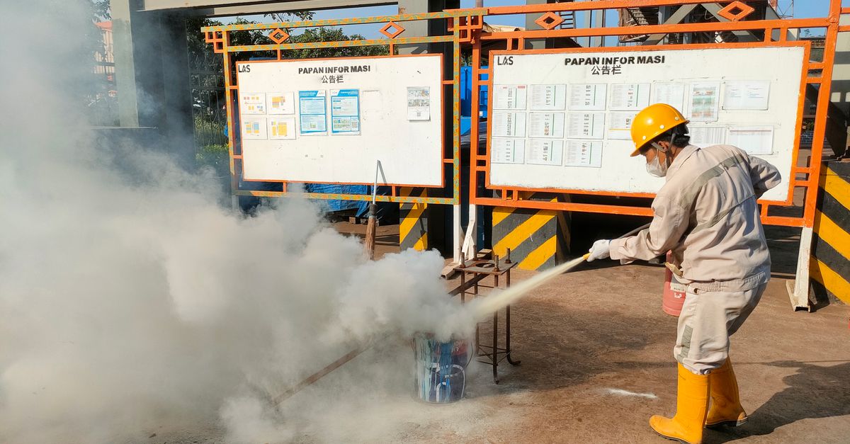 Worker conducts fire safety training outdoors with extinguishers.