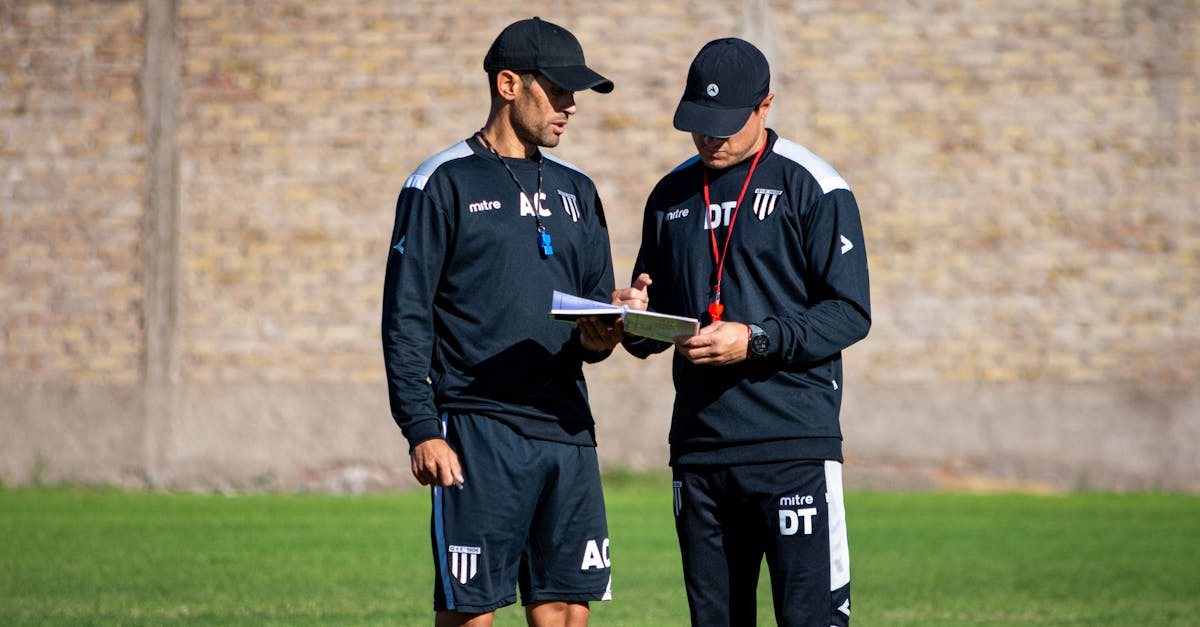 Two soccer coaches reviewing strategies on the field during the day.