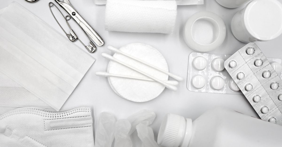A flat lay of essential first aid supplies including bandages, gloves, and medications.