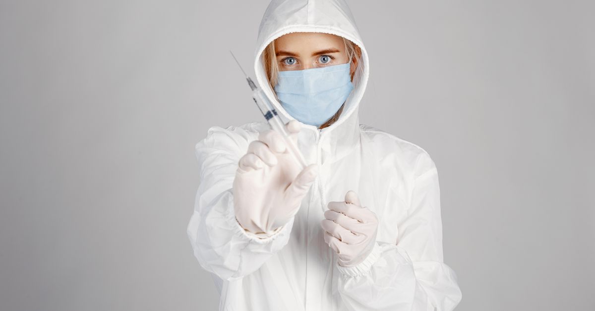 A healthcare professional in protective gear holding a syringe, emphasizing safety and preparedness.