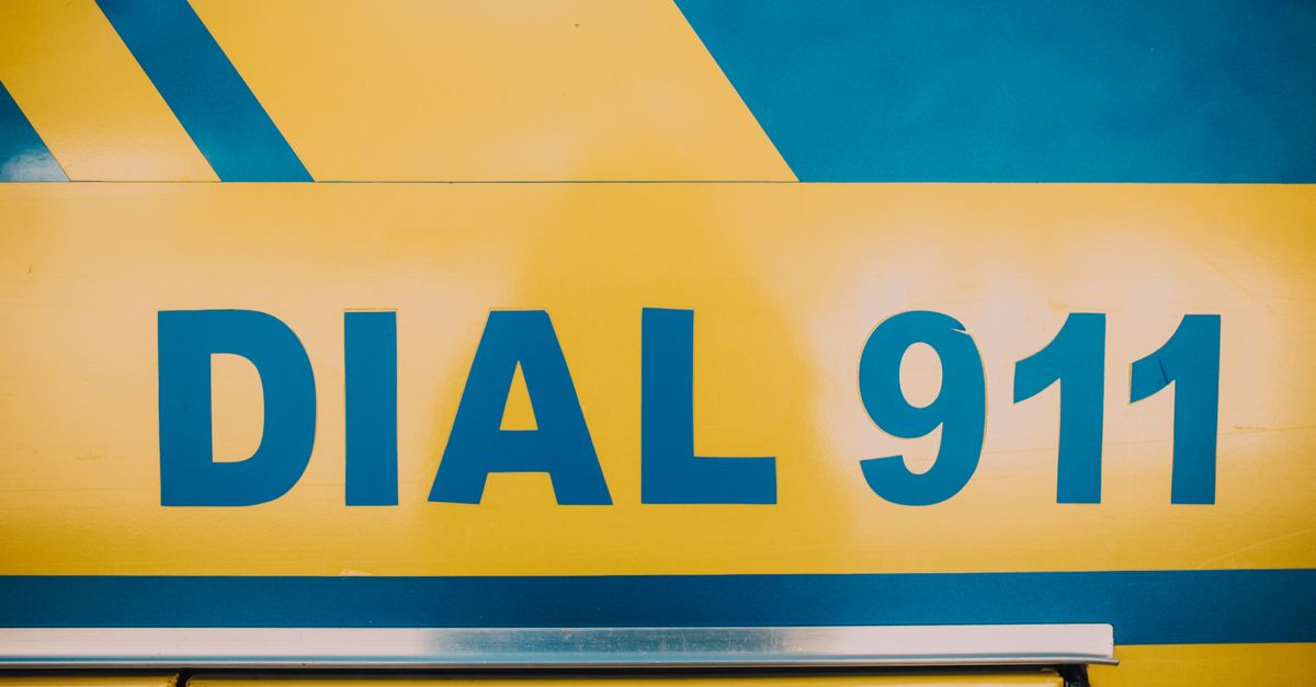 Close-up of 'Dial 911' emergency sign on a vehicle with bold yellow and blue colors.