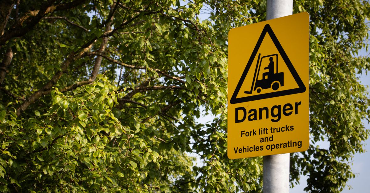 Yellow warning sign indicating forklift trucks and vehicles operating in the area.