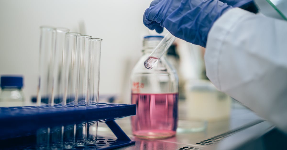 Scientist in laboratory handling test tube with pink liquid for scientific research.