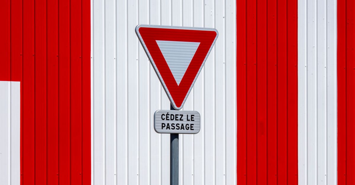 A French 'Yield' sign against a red and white striped wall, minimalistic design.