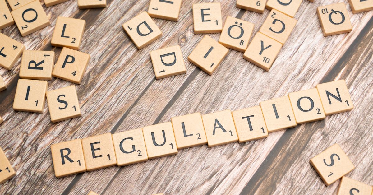 Wooden letter tiles spelling 'Regulation' on a textured wood background, conveying themes of compliance and structure.