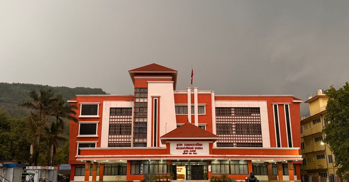 A striking red government building stands under an overcast sky, featuring modern architecture.