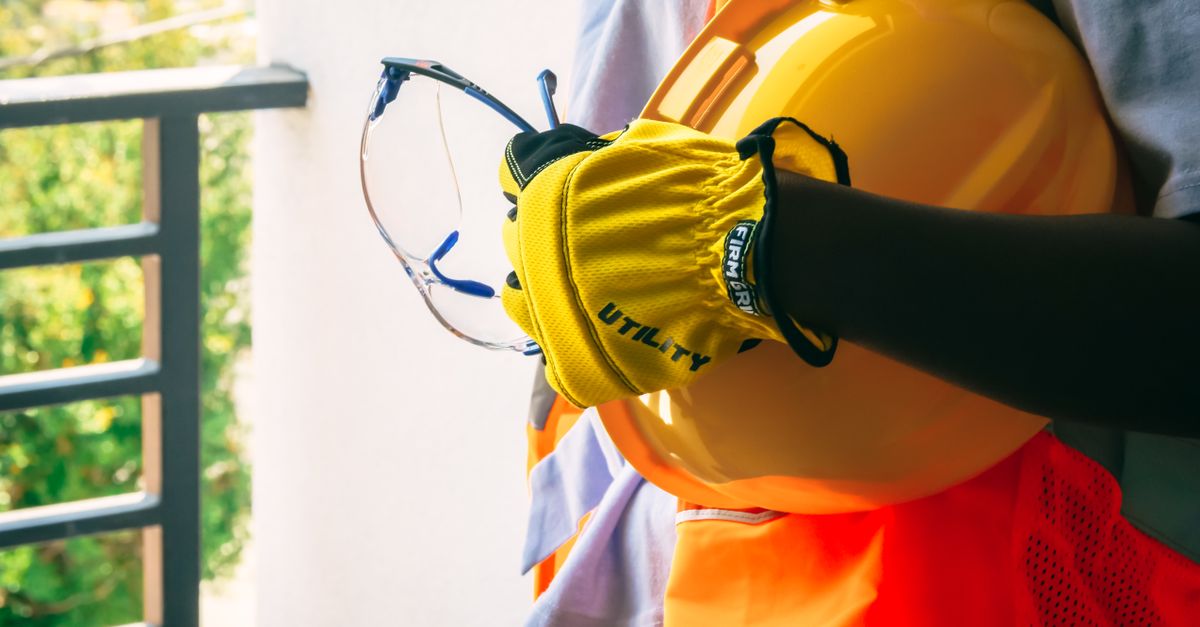 Construction worker with safety gear including helmet and gloves.