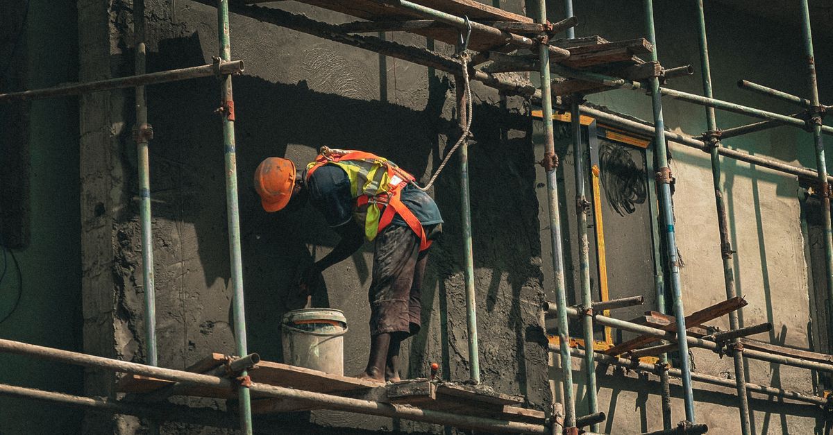 A construction worker applies plaster on a building facade in Abuja, Nigeria.