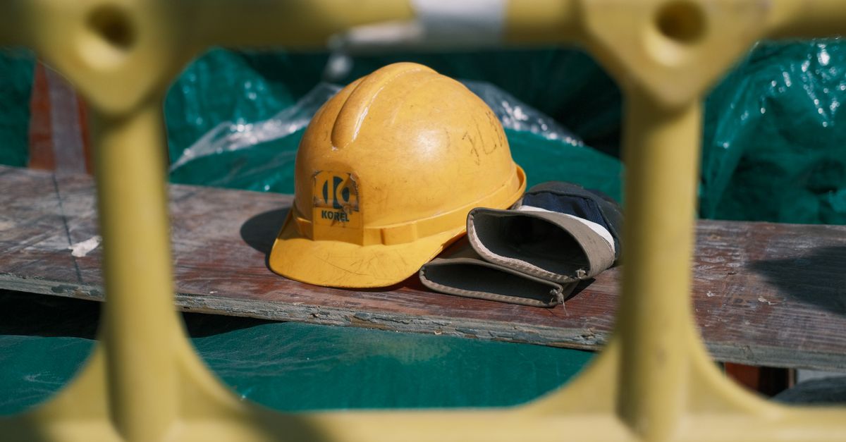 Close-up of a yellow construction helmet on a workbench at a building site.