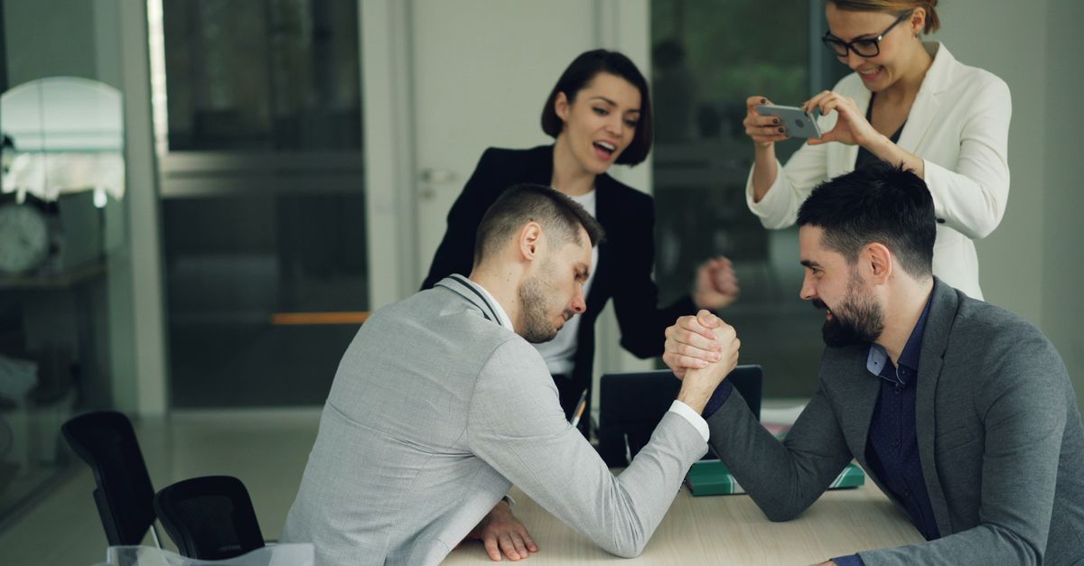 Colleagues cheer during a fun office arm wrestling challenge, fostering team spirit.