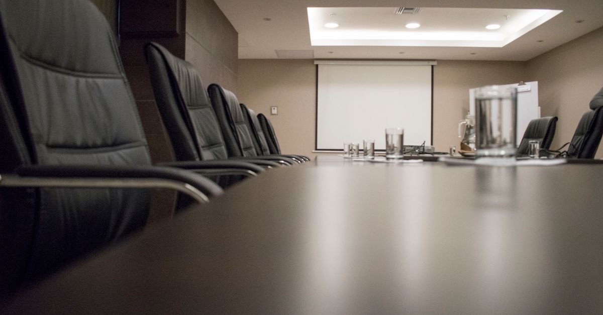 Empty conference room with black chairs, projector, and glasses on table. Ideal for business meetings.