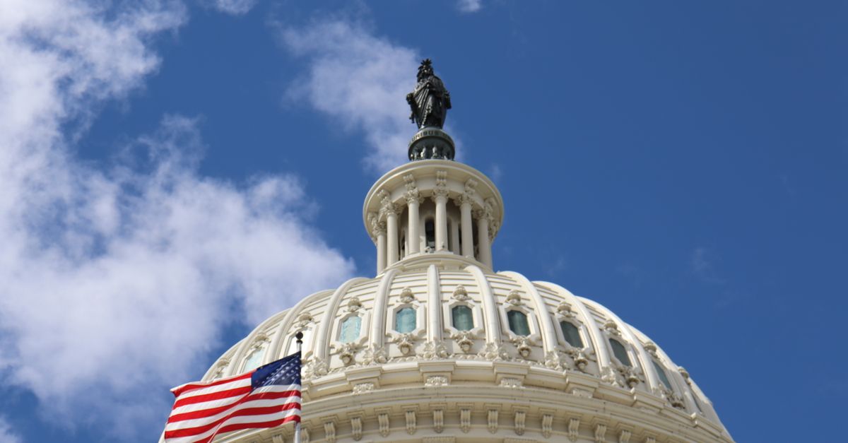 Capture of the U.S. Capitol dome with an American flag waving against a blue sky in Washington, D.C.