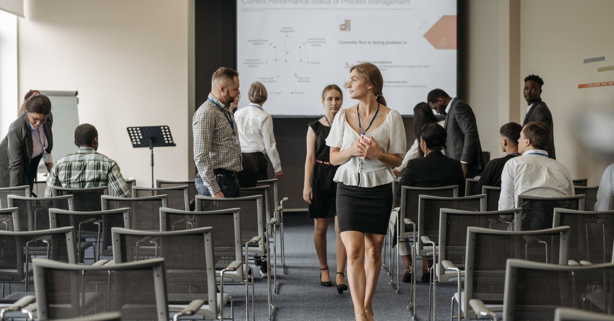 Professionals at a business conference engage before a presentation in a modern office.