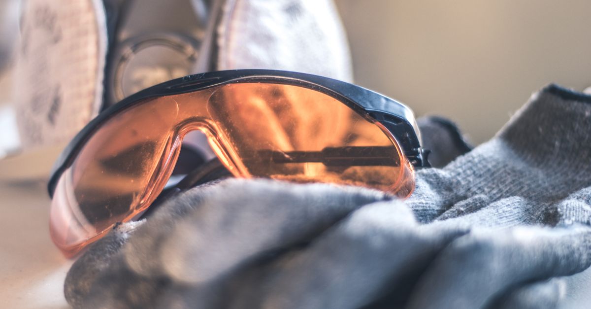 Close-up of safety glasses and gloves with a respirator, highlighting protective equipment.