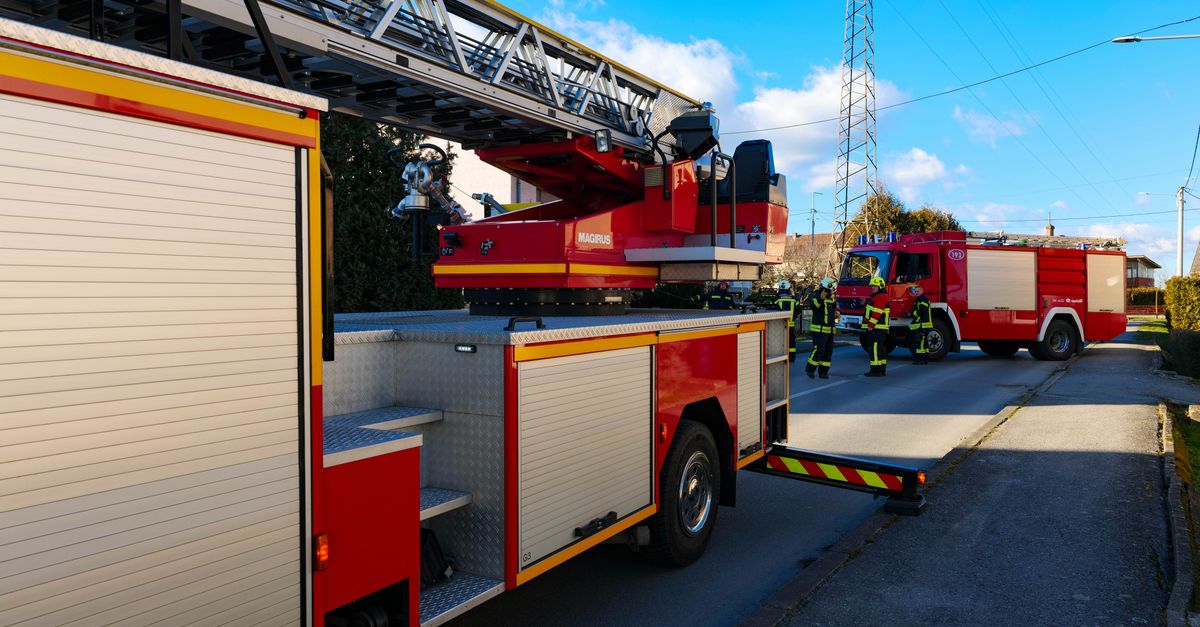 Firefighters and firetrucks in action on a city street under clear blue skies.
