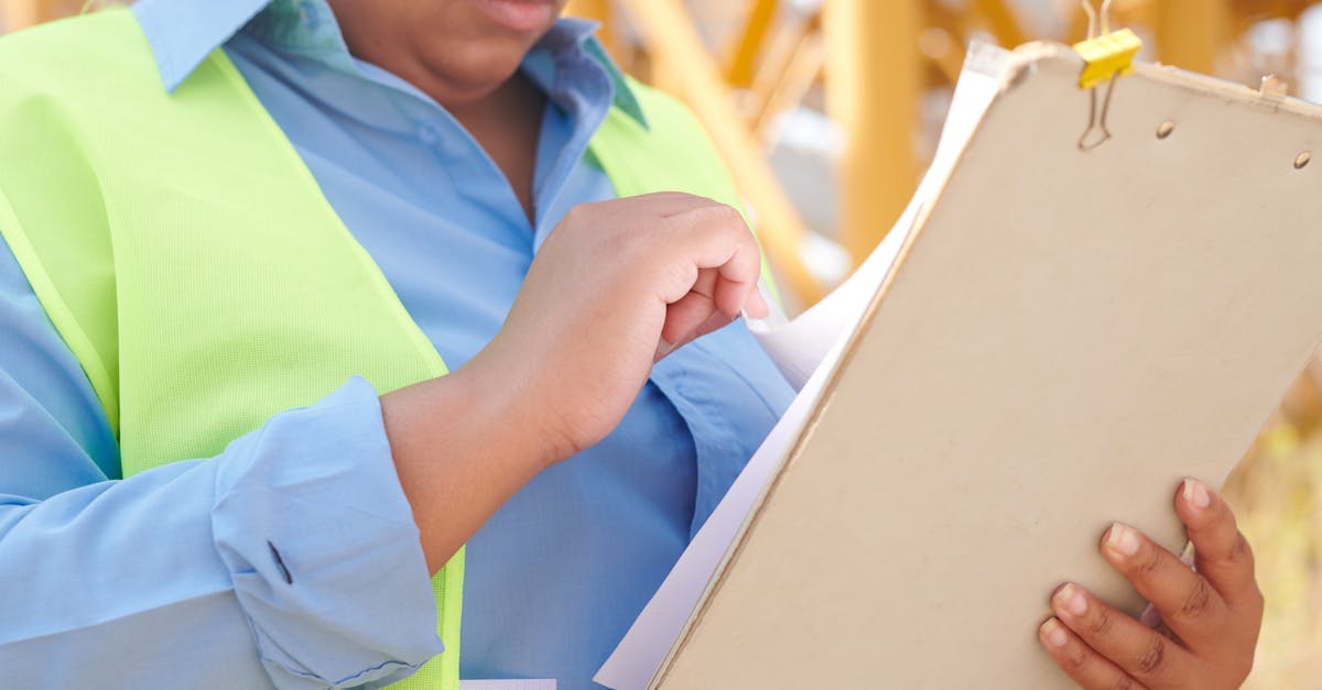 A female engineer in safety gear reviewing documents on a clipboard at a construction site.