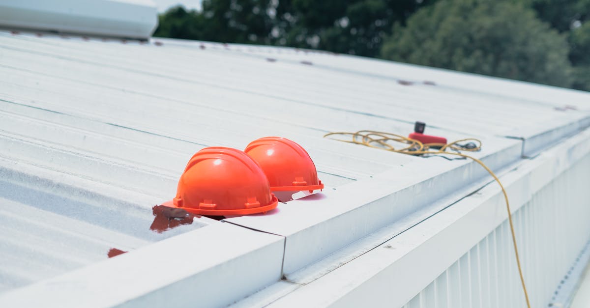 Red hard hats and safety equipment on a metal roof, emphasizing construction safety.