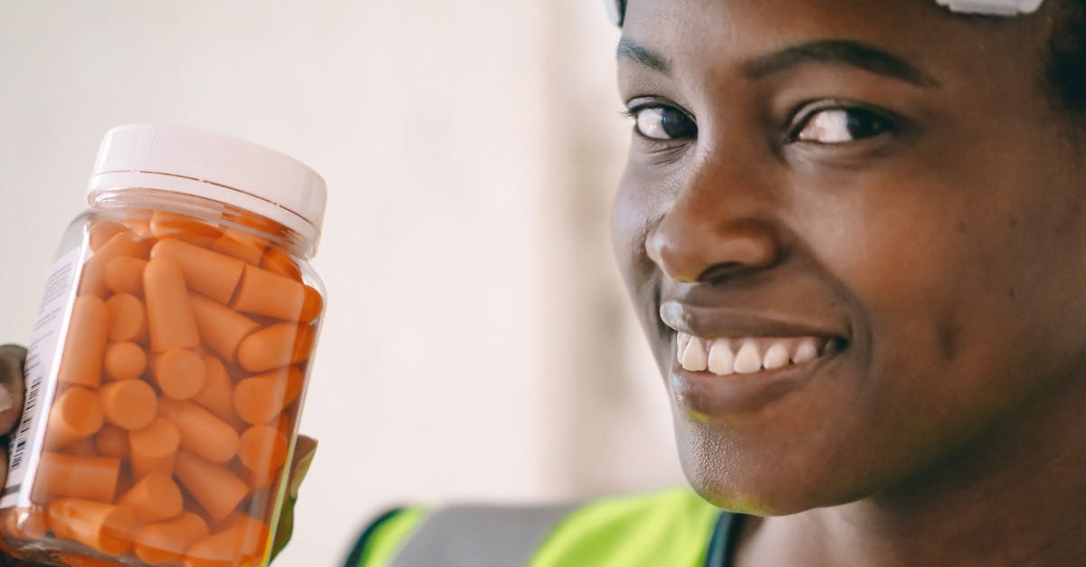 Close-up of a smiling construction worker holding a jar of earplugs.
