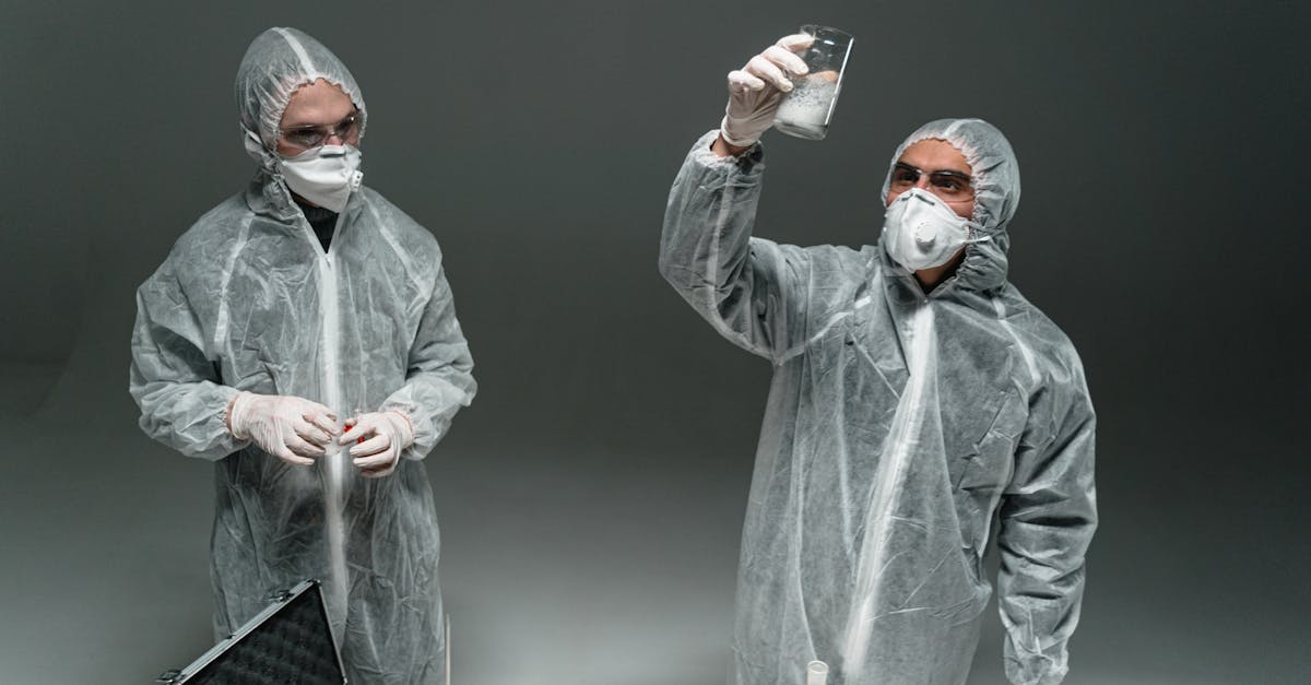 Two scientists in PPE conducting an experiment indoors with lab equipment.