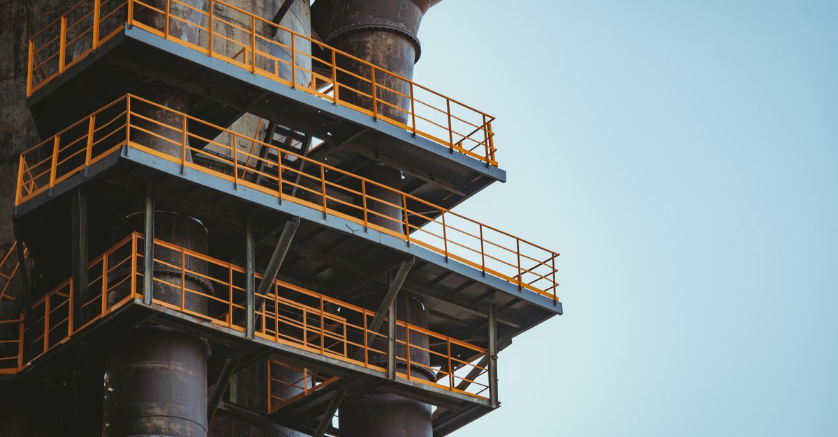 Close-up view of industrial metal balconies and pipes against a clear sky.
