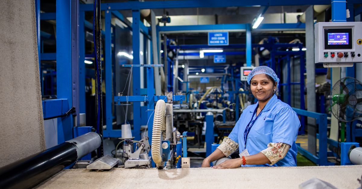 Female worker operates machinery in a textile factory, showcasing industry and teamwork.
