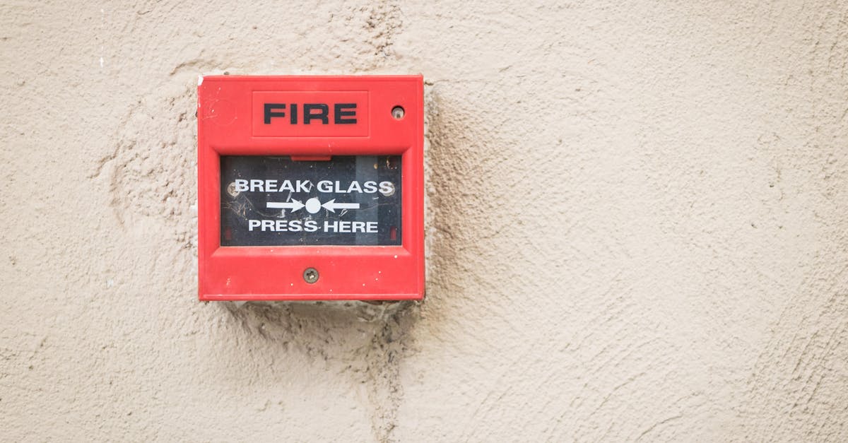 Close-up of a red fire alarm mounted on a textured wall, ready for emergency use.