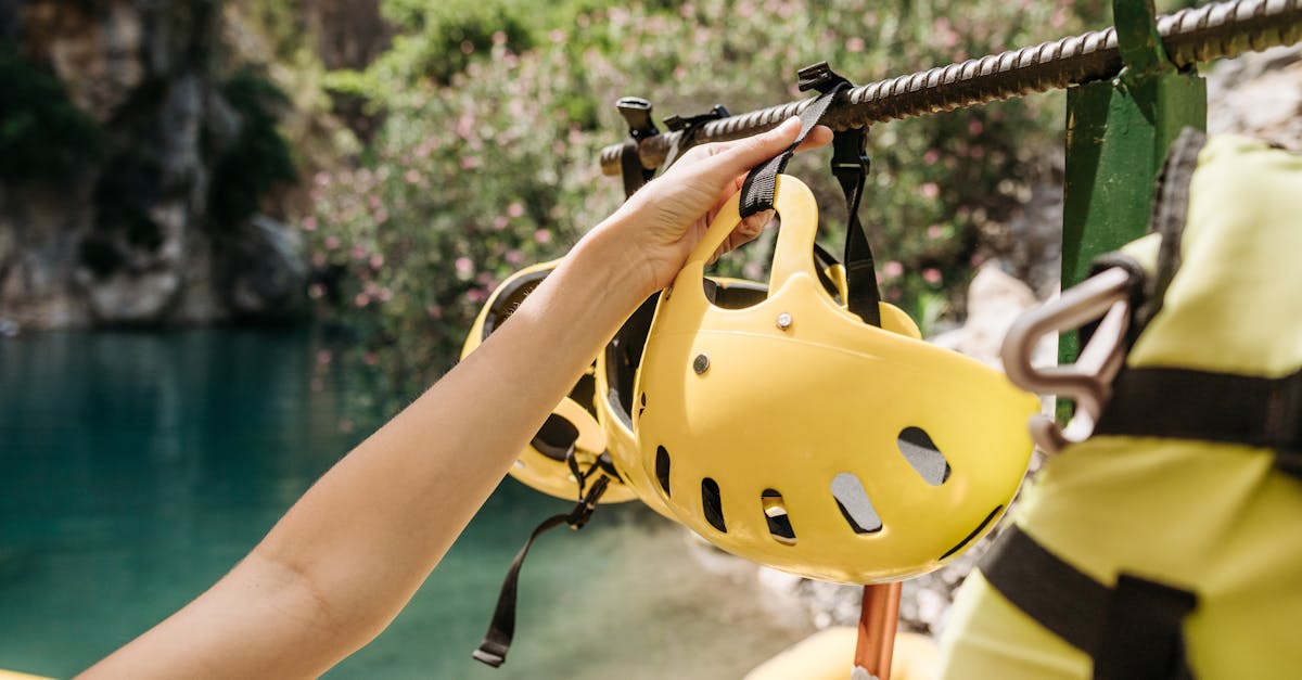 Close-up of a person holding a yellow helmet near a scenic outdoor location with water.