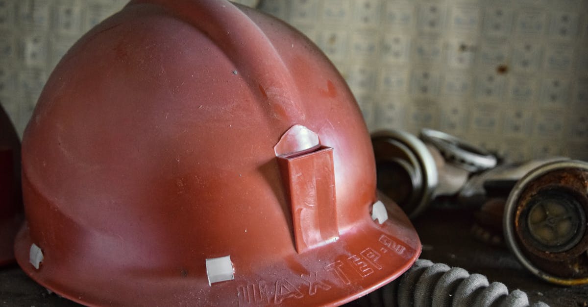 Close-up of a red safety helmet and filter mask in an industrial setting.