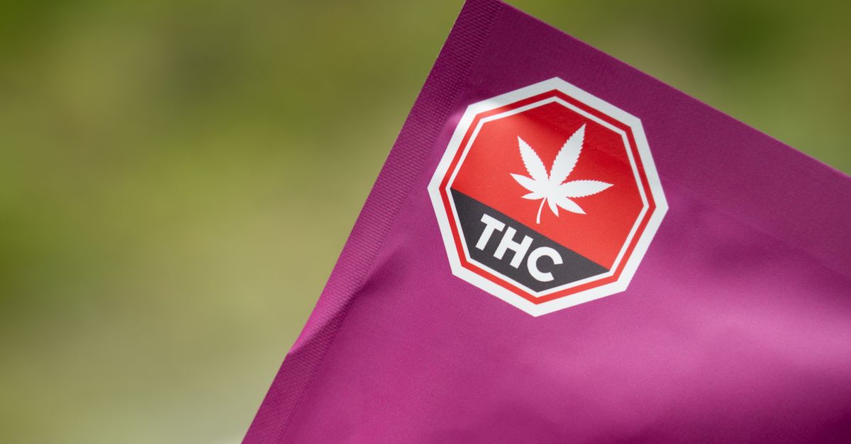Close-up of cannabis packaging with a THC warning label on a purple background, highlighting safety and regulatory compliance.