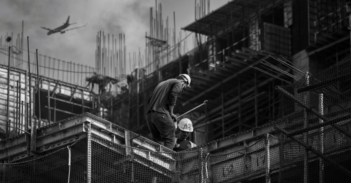 Black and white photo showing construction workers on an urban building site.
