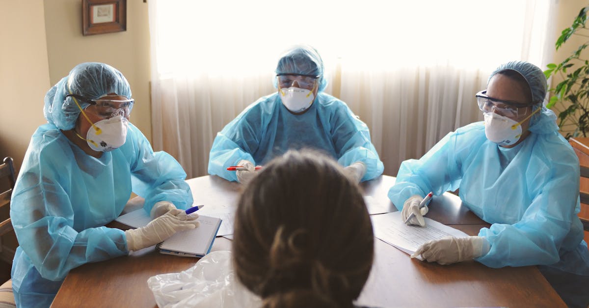 Three healthcare professionals in PPE discuss patient care indoors.