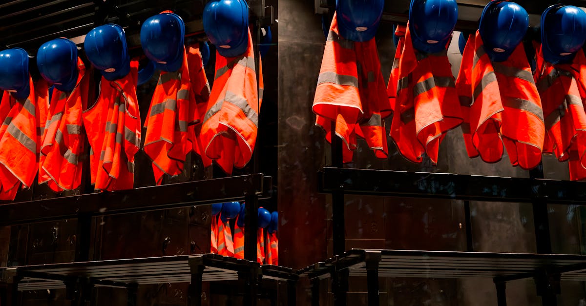 Row of orange safety vests and blue helmets hanging in industrial setting