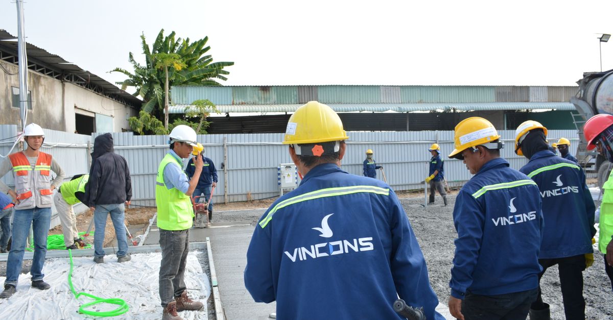 Group of construction workers wearing hard hats assessing a site outdoors.