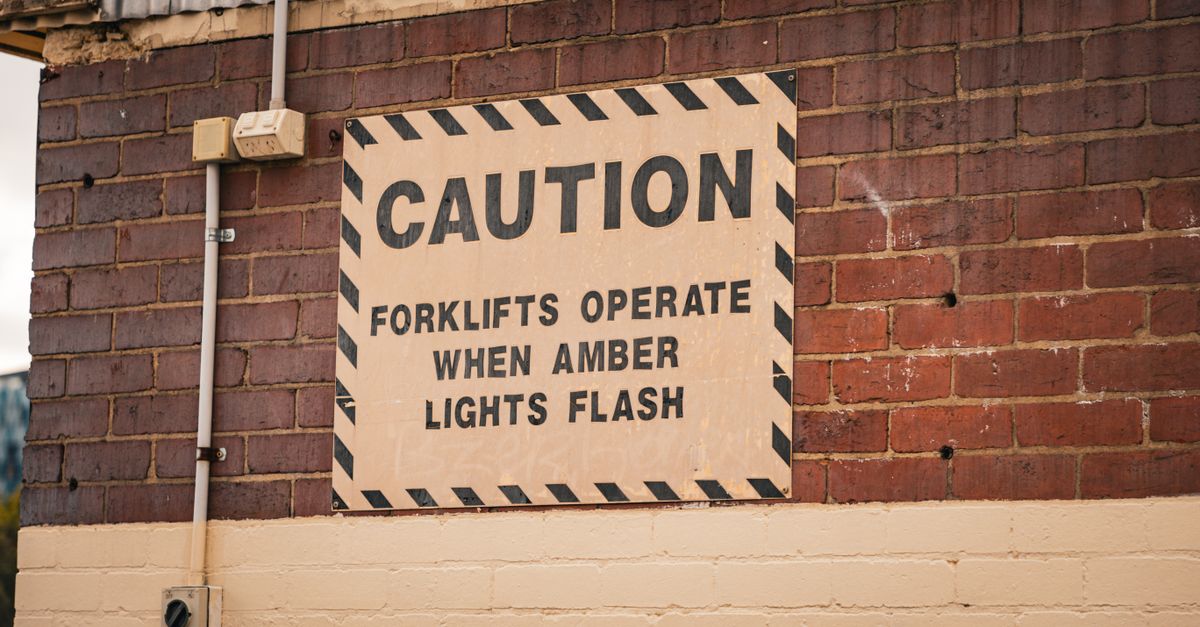 Caution sign on a brick wall indicating forklift operation safety in Melbourne.