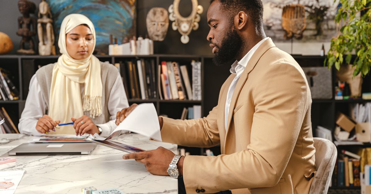 Two professionals discussing documents in a modern office, showcasing teamwork and collaboration.