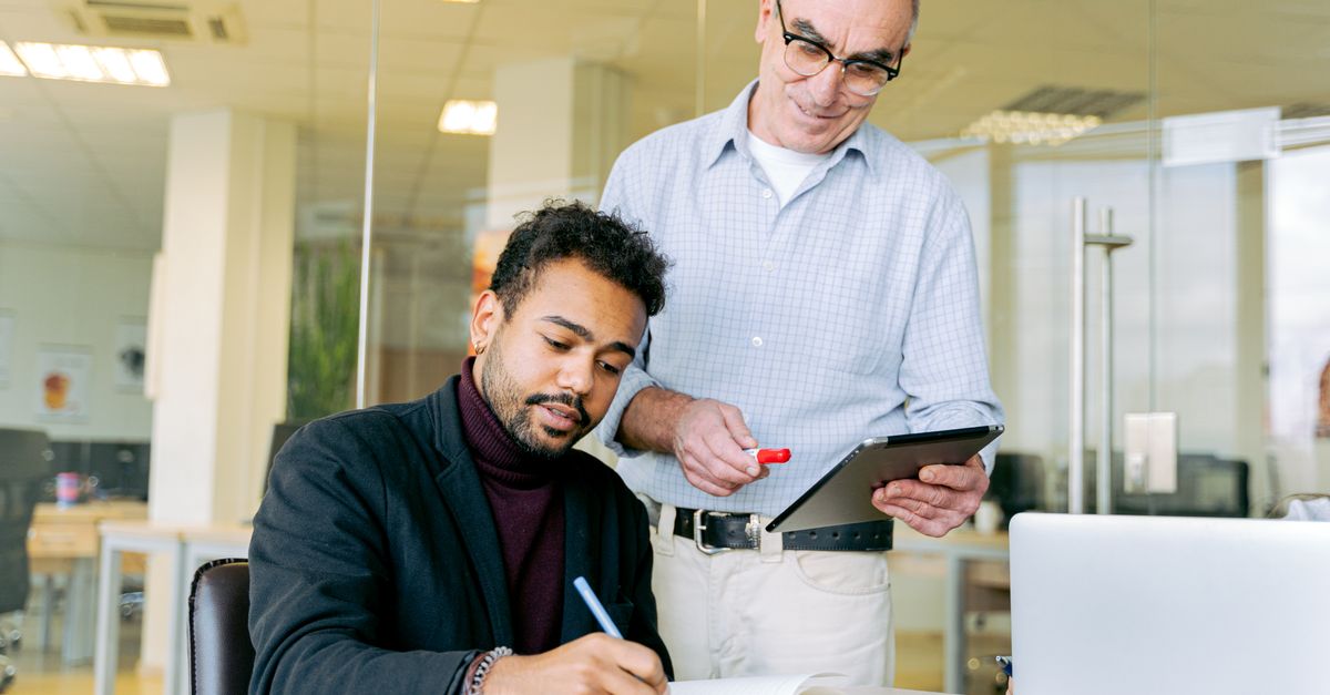 A professional interaction between two colleagues in a modern office environment, highlighting teamwork and communication.